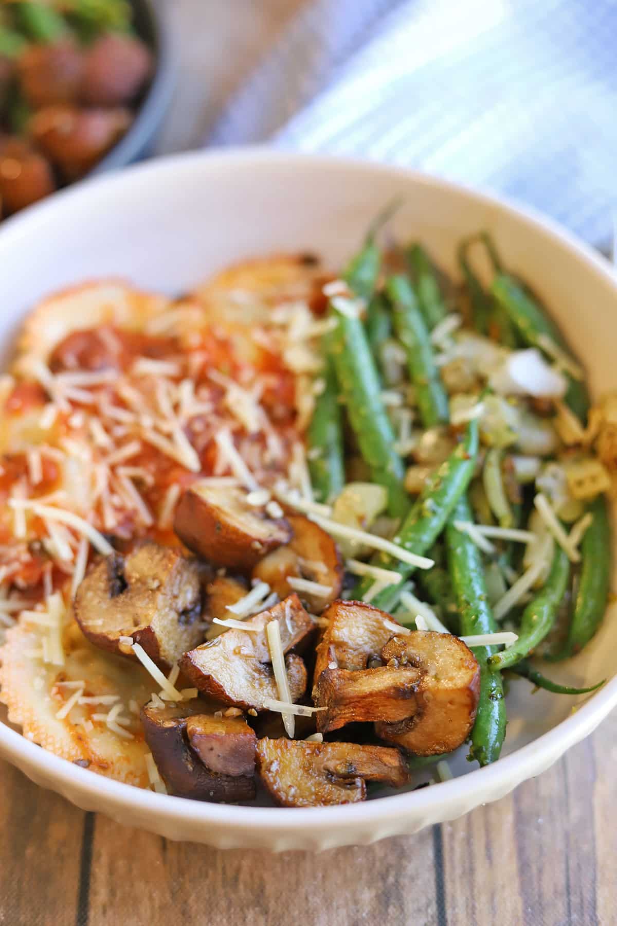 Air fryer mushrooms with ravioli, green beans, and topped with vegan parmesan.