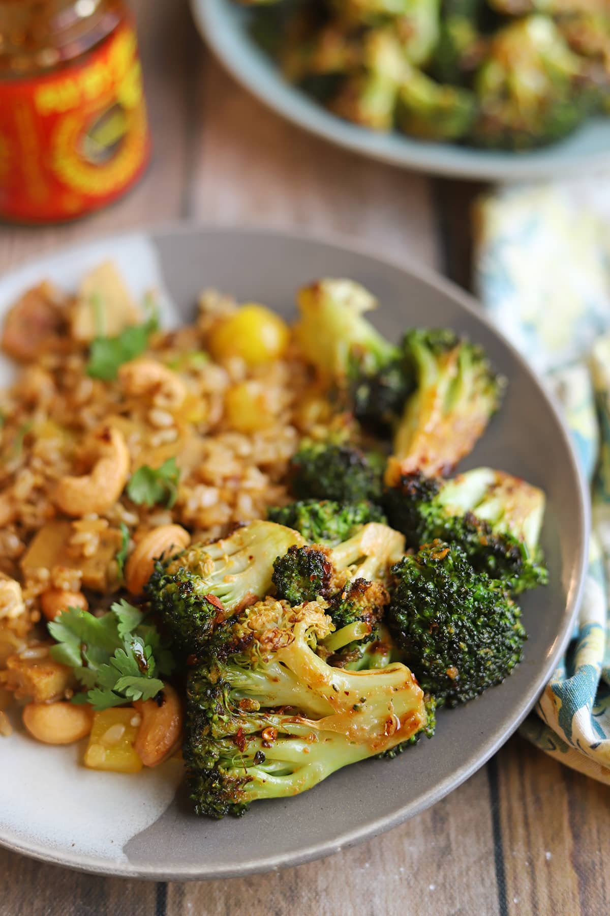 Chili crisp coated roasted broccoli side dish on plate with fried rice.