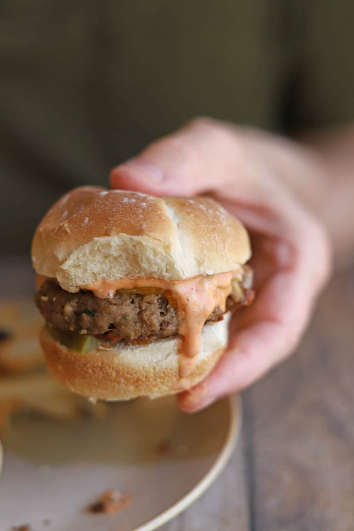 Hand holding veggie burger with vegan Big Mac sauce topping.