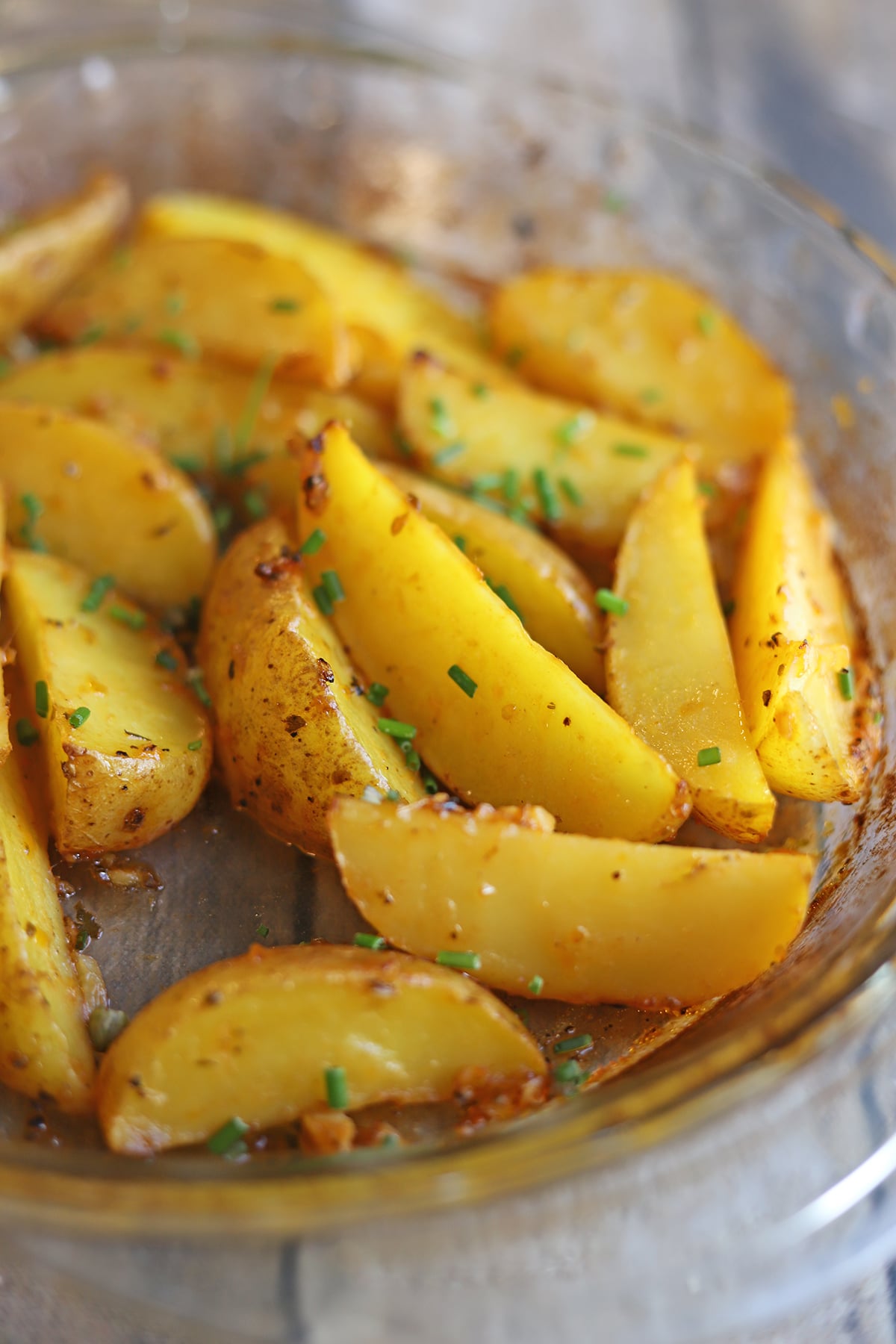 Wedges of roasted garlic lemon yellow potatoes, garnished with chives.