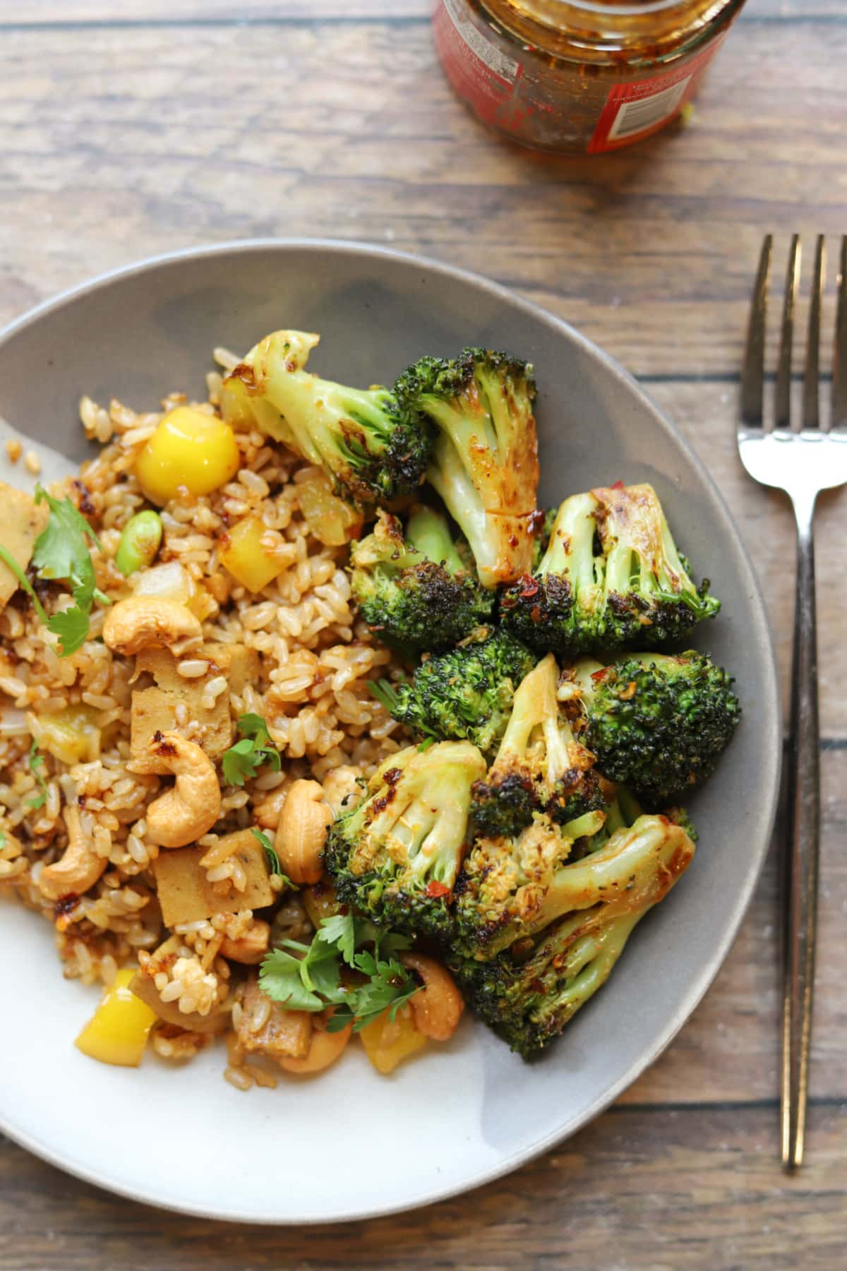 Roasted broccoli with chili crisp on plate with fried rice.