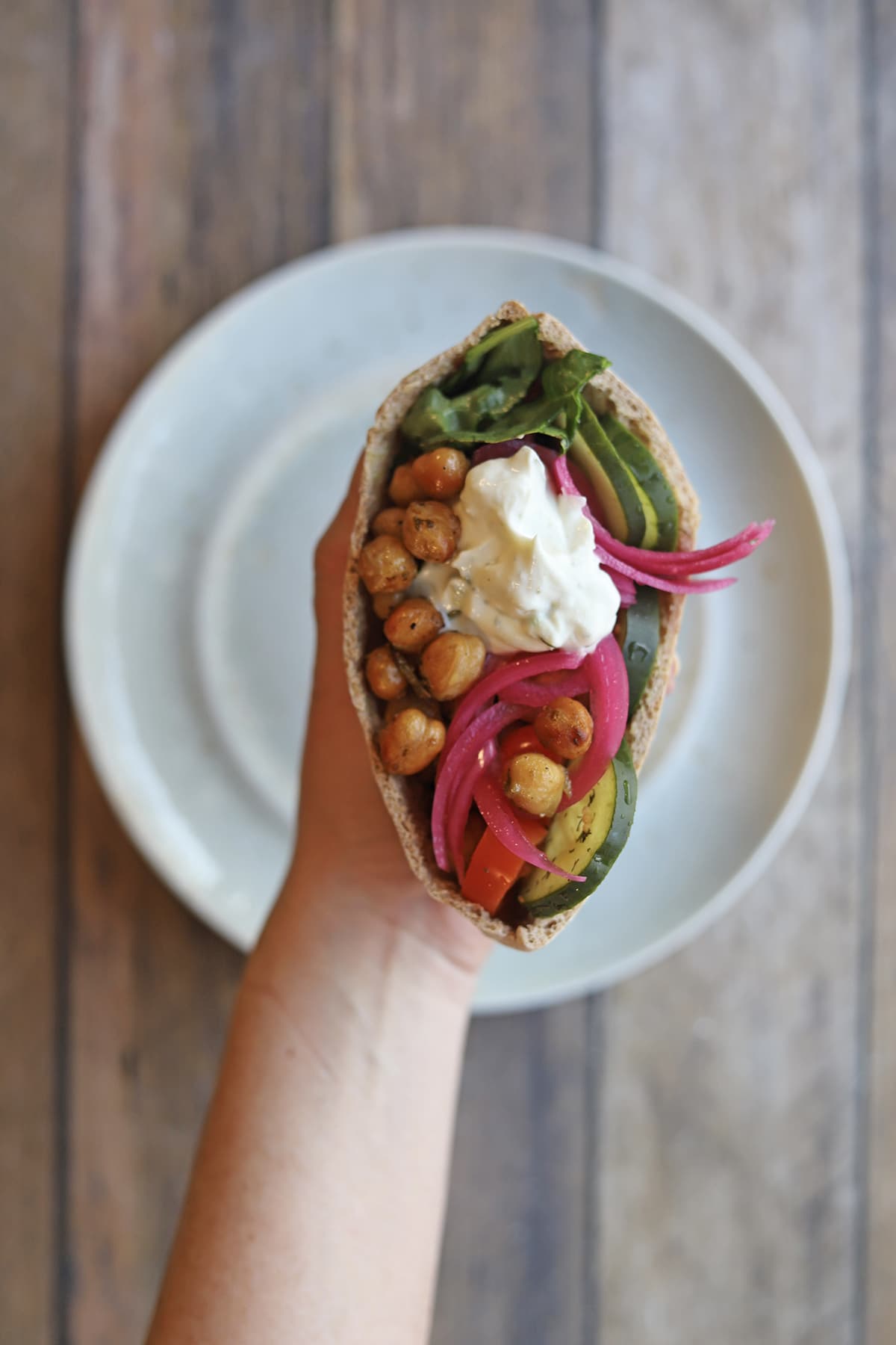 Hand holding roasted chickpea pita pocket with veggies.