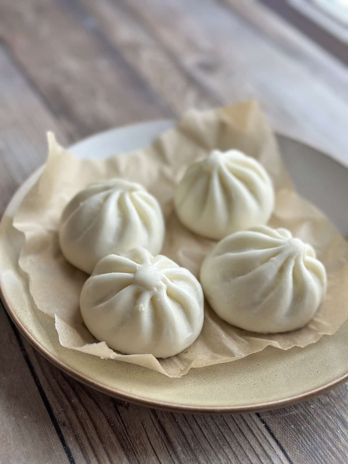 Steamed bao on parchment paper.