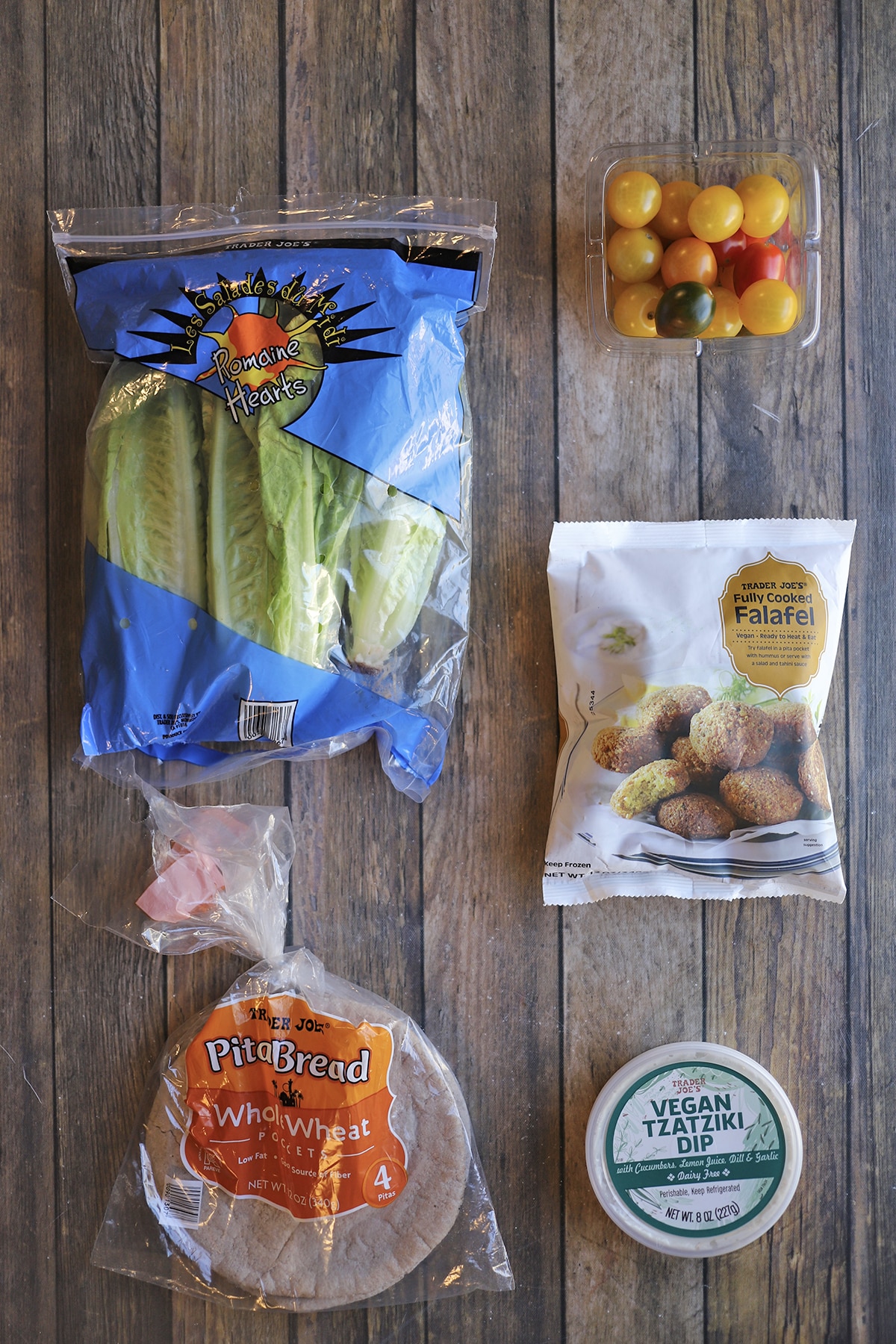 Trader Joe's falafel, cherry tomatoes, romaine, pita bread, and vegan tzatziki dip on table.
