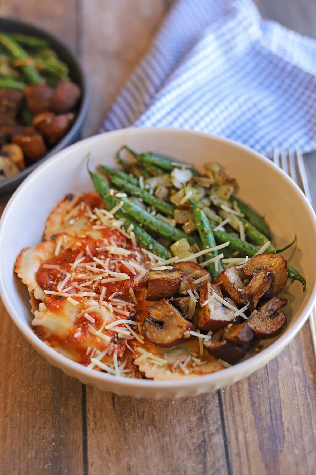 Trader Joe's vegan ravioli in bowl with air fryer mushrooms and pesto green beans.