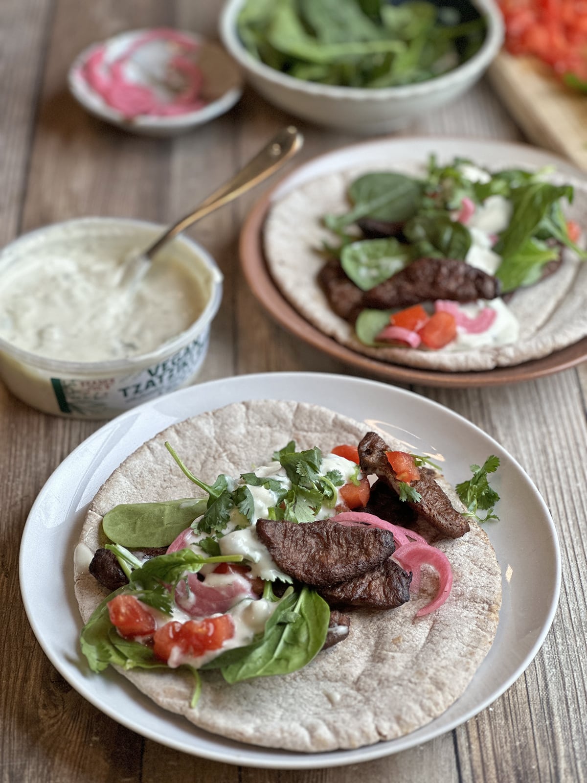 Vegan steak gyros with beefless bulgogi, spinach, vegan tzatziki, and tomatoes.