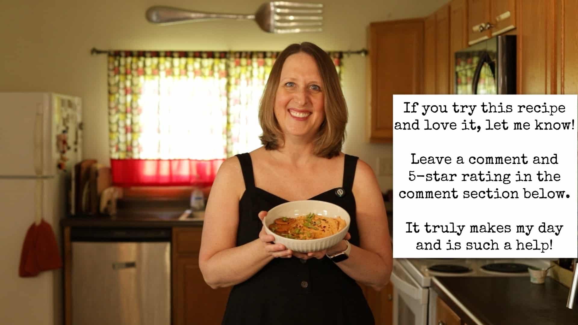 Cadry holding pizza-flavored sun-dried tomato hummus in kitchen. Text overlay, "If you try this recipe and love it, let me know! Leave a comment and 5-star rating in the comment section below. It truly makes my day and is such a help!"