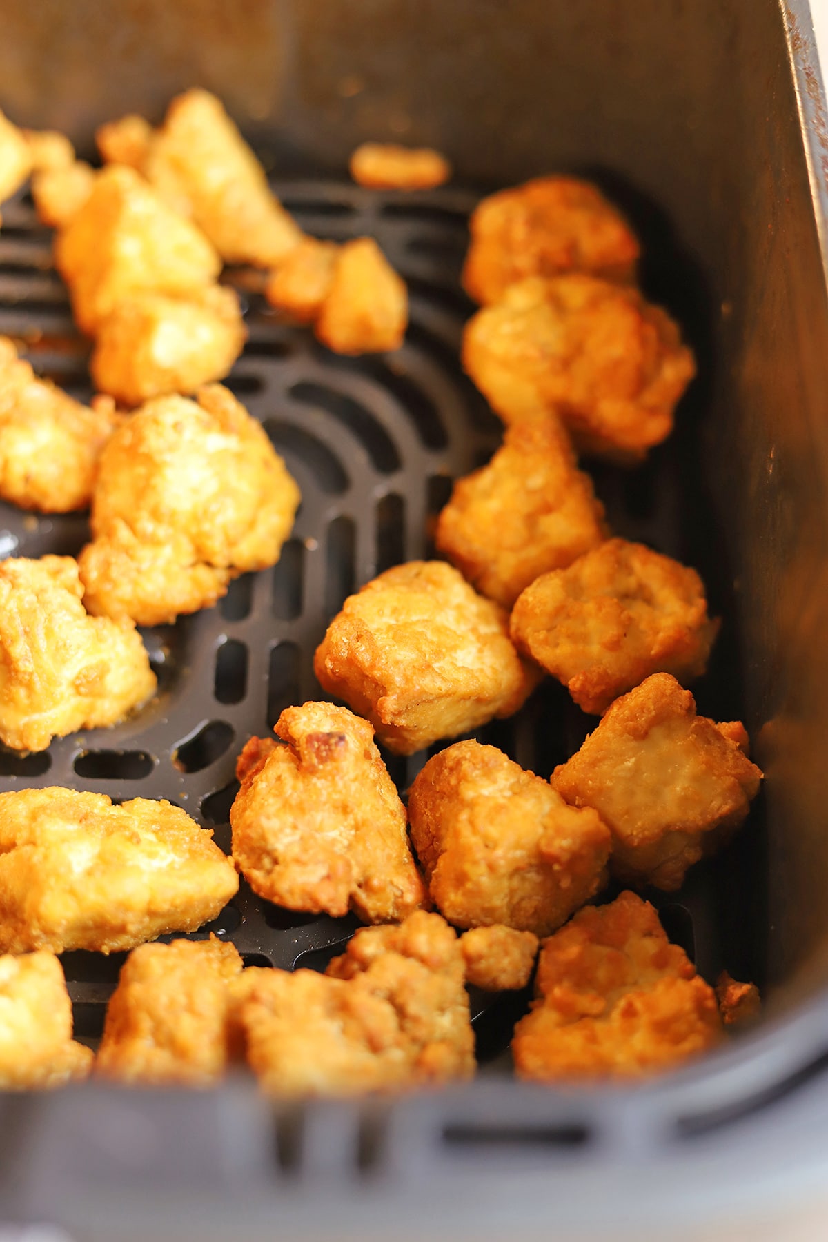 Crunchy tofu nuggets in air fryer basket.