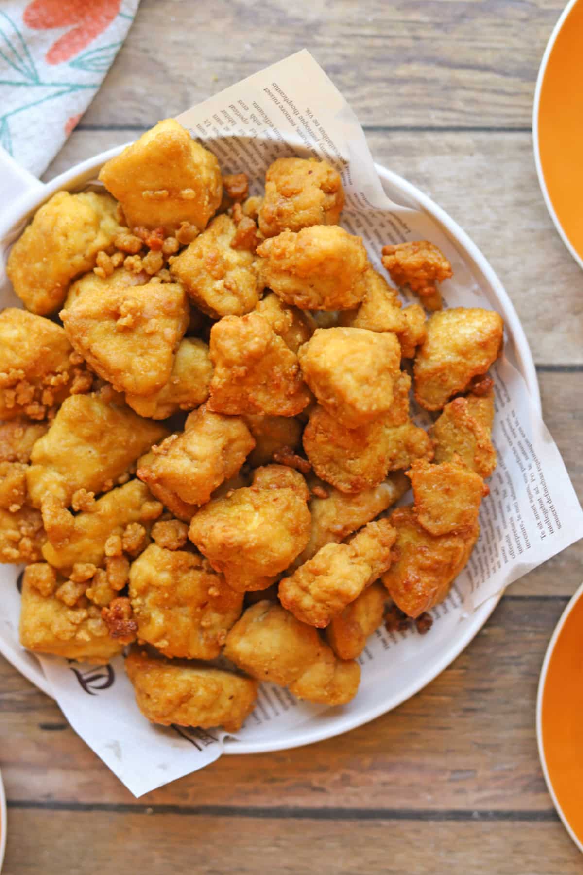 Jagged tofu bites in crispy, gluten-free coating on plate lined with paper.