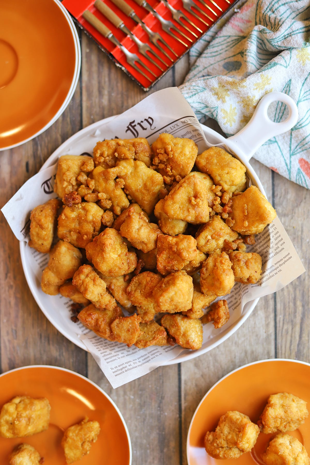 Platter of crispy tofu nuggets on platter by forks and appetizer plates.