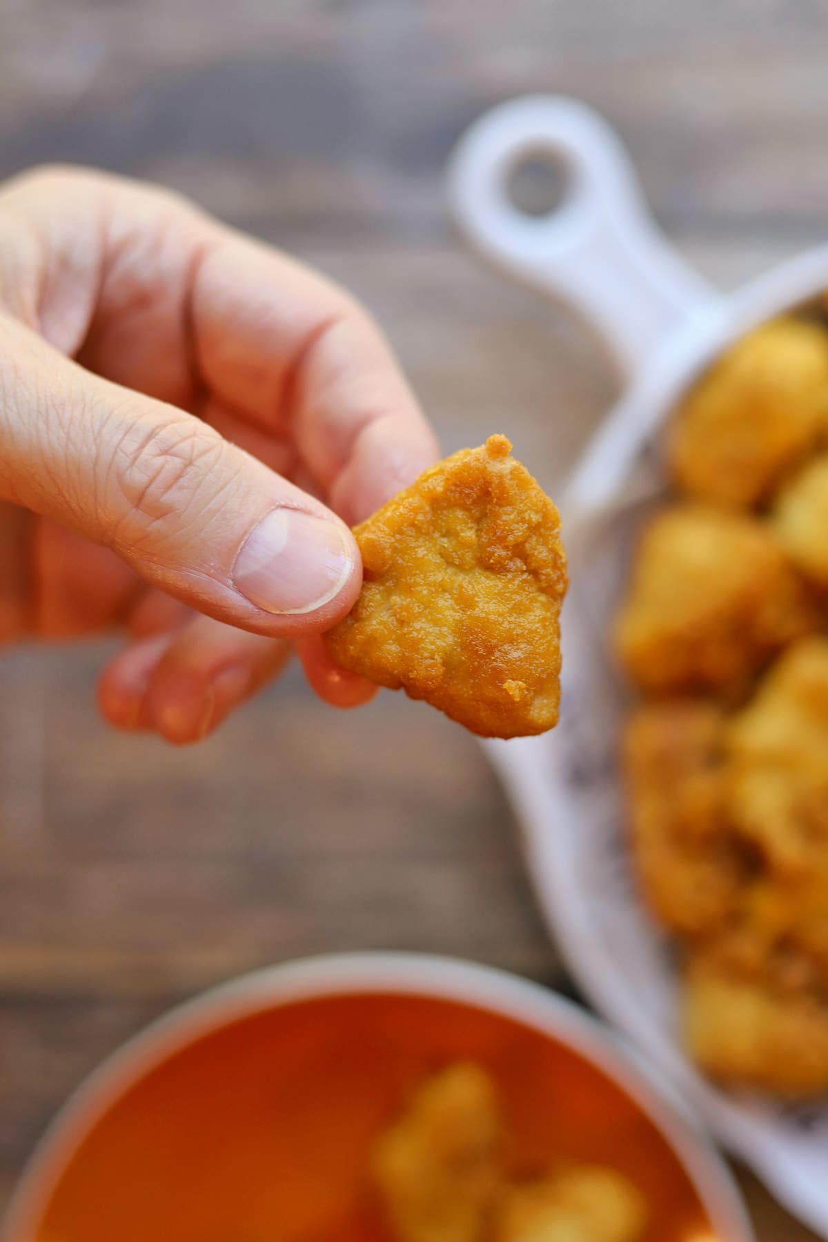 Hand holding air fryer tofu nugget with crispy breading.