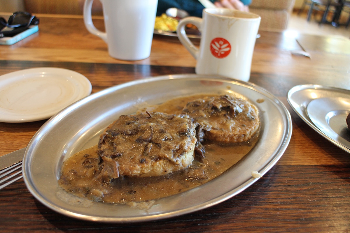 Biscuits covered in mushroom gravy on metal plate.