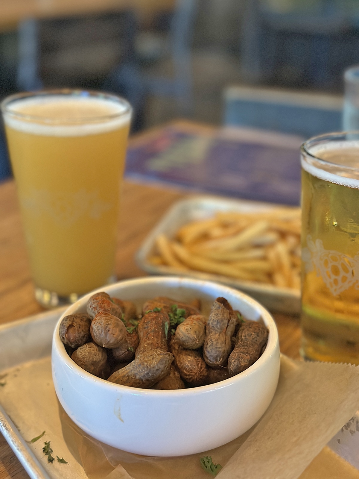 Boiled peanuts and fries with glasses of beer.