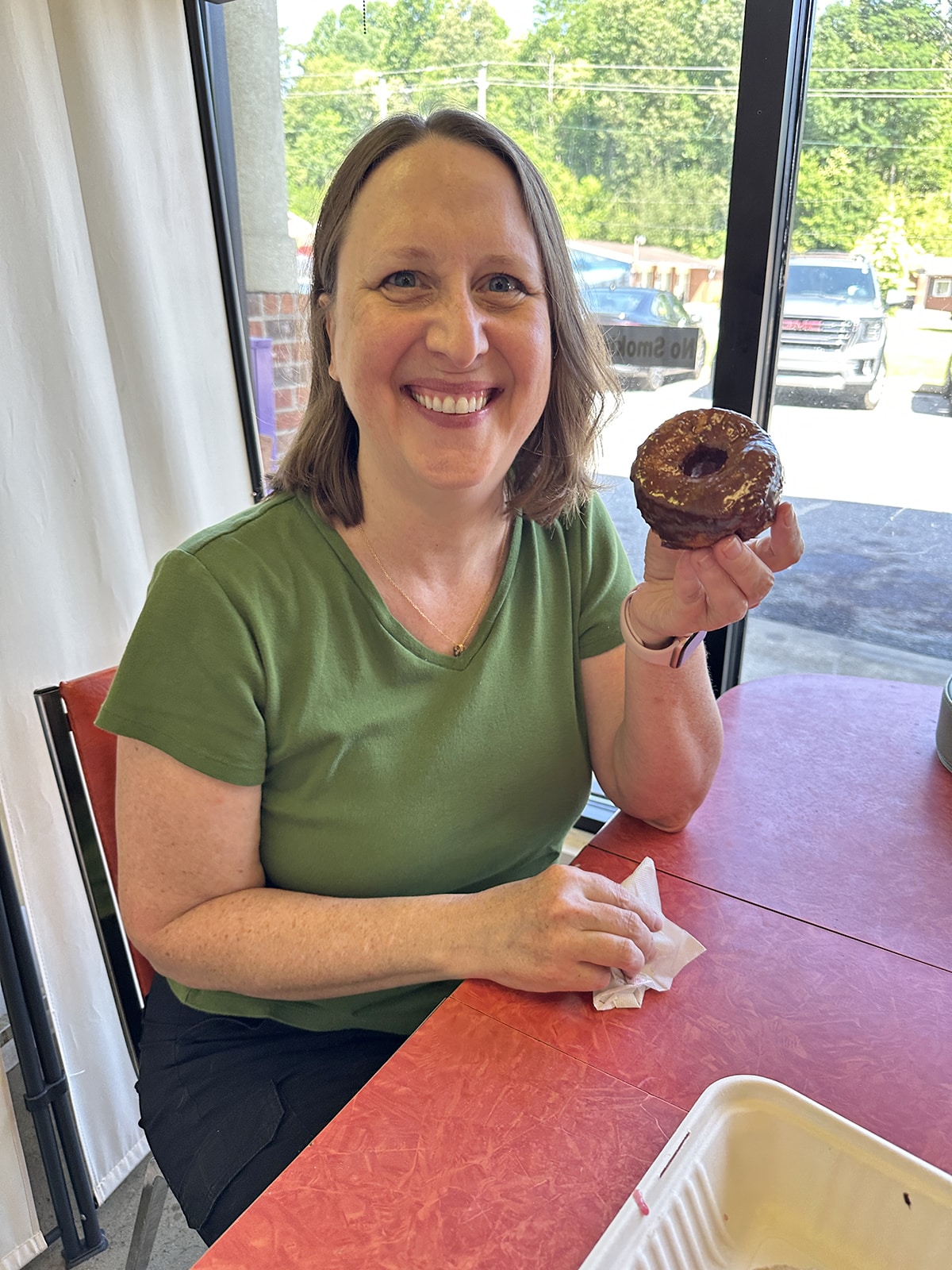 Cadry holding chocolate glazed donut.