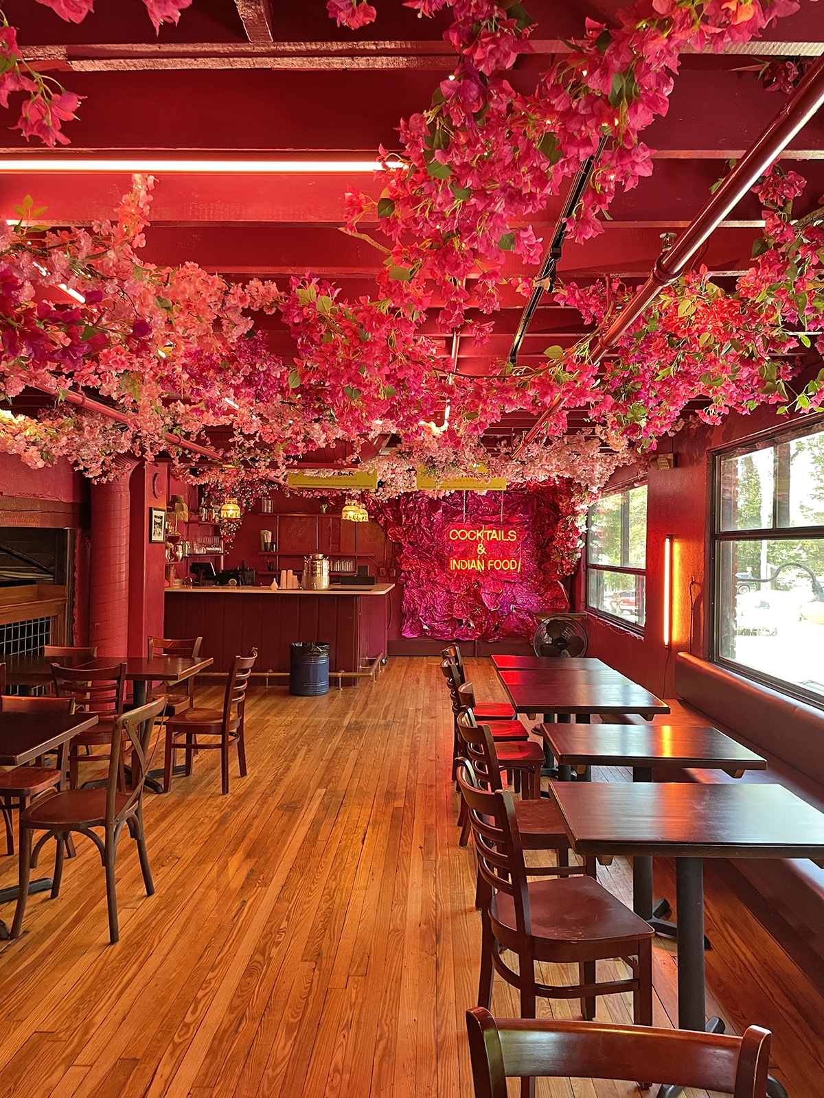 Pink flowers along ceiling in room with tables at Chai Pani.