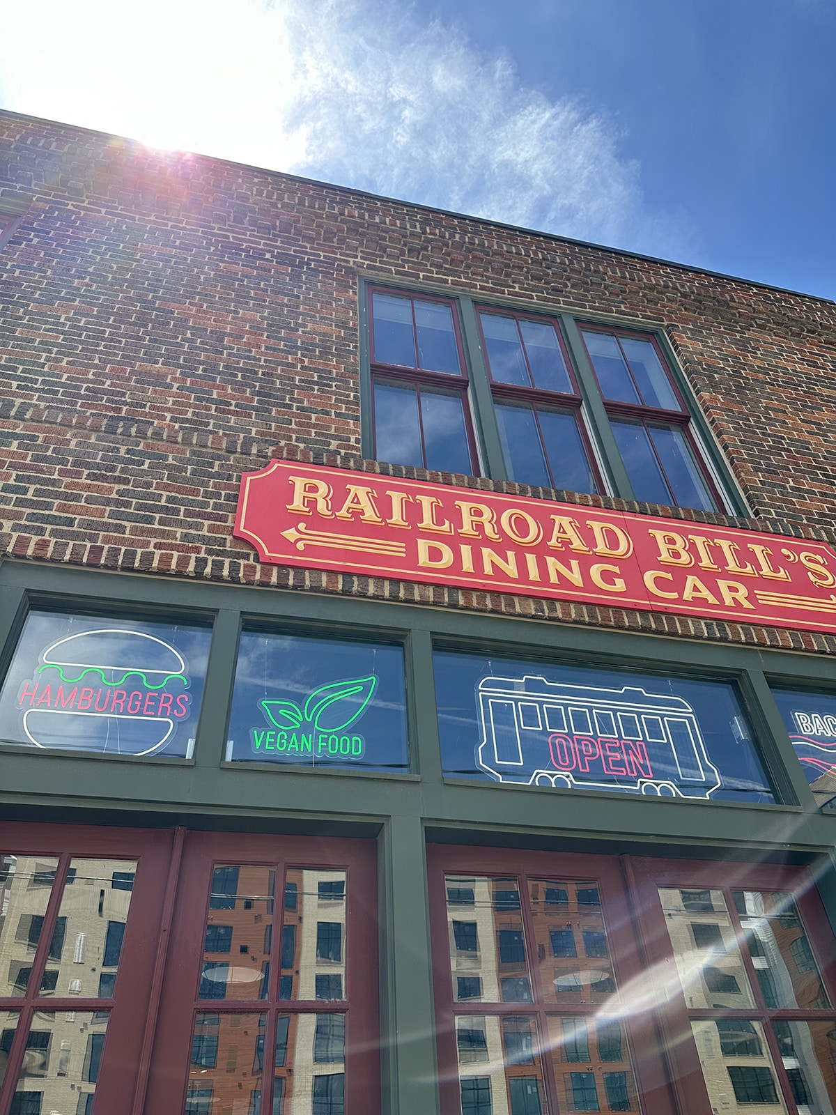 Exterior Railroad Bill's Dining Car with neon lights for hamburgers, vegan food, and an open sign.