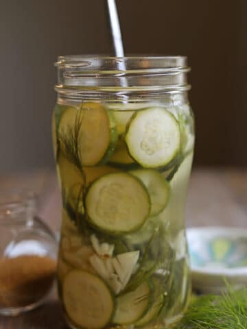 Easy pickled zucchini in jar with dill, garlic, and mustard seeds.