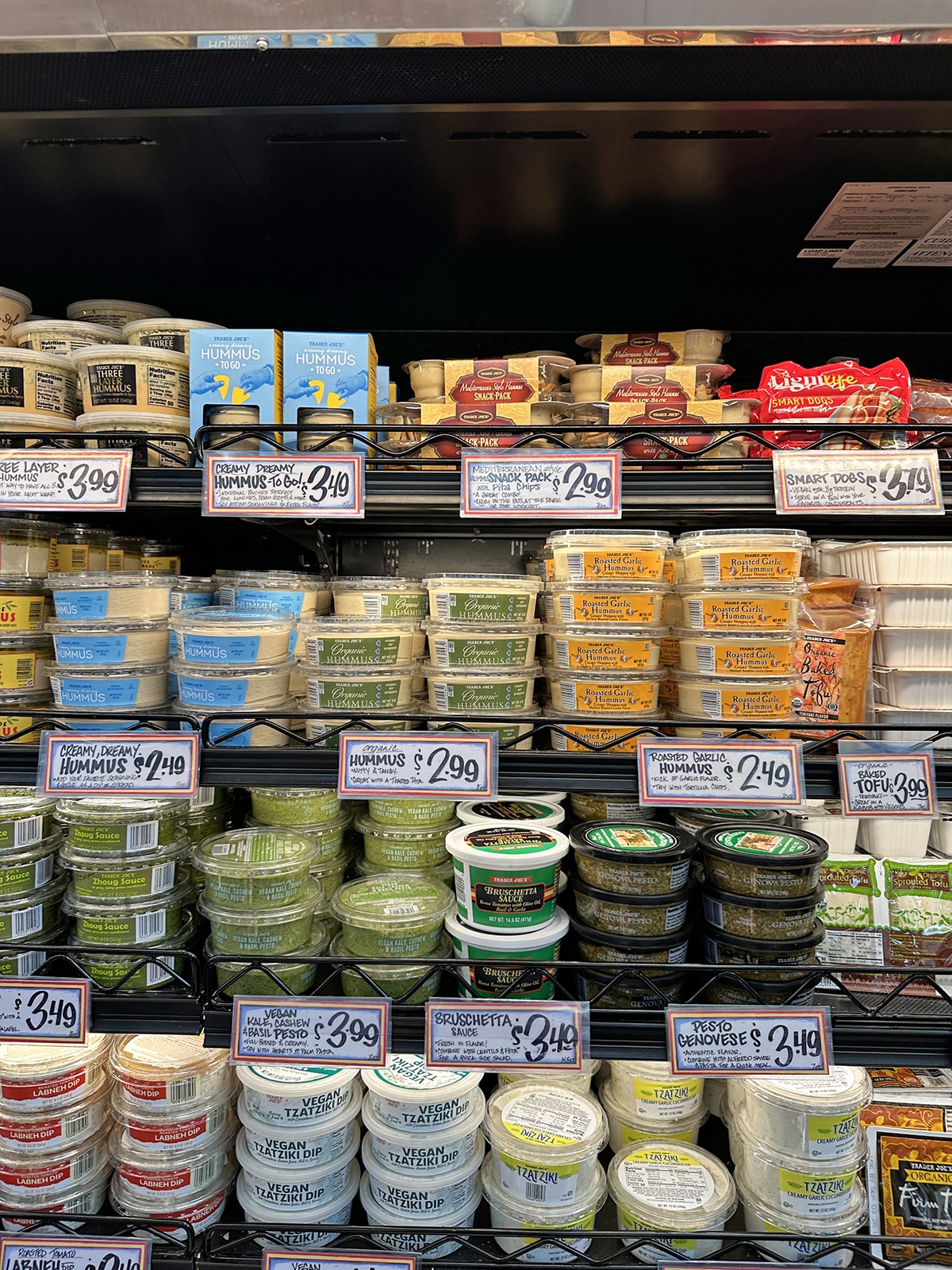 Hummus, bruschetta, kale pesto, zhoug sauce, and vegan tzatziki in refrigerated case.