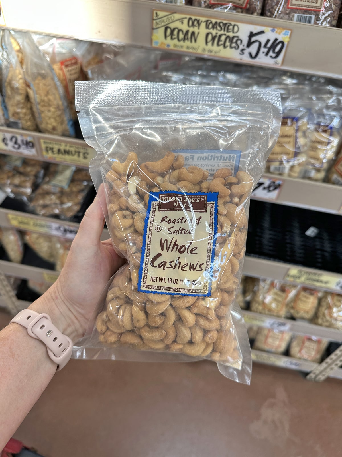 Hand holding package of roasted and salted whole cashews.
