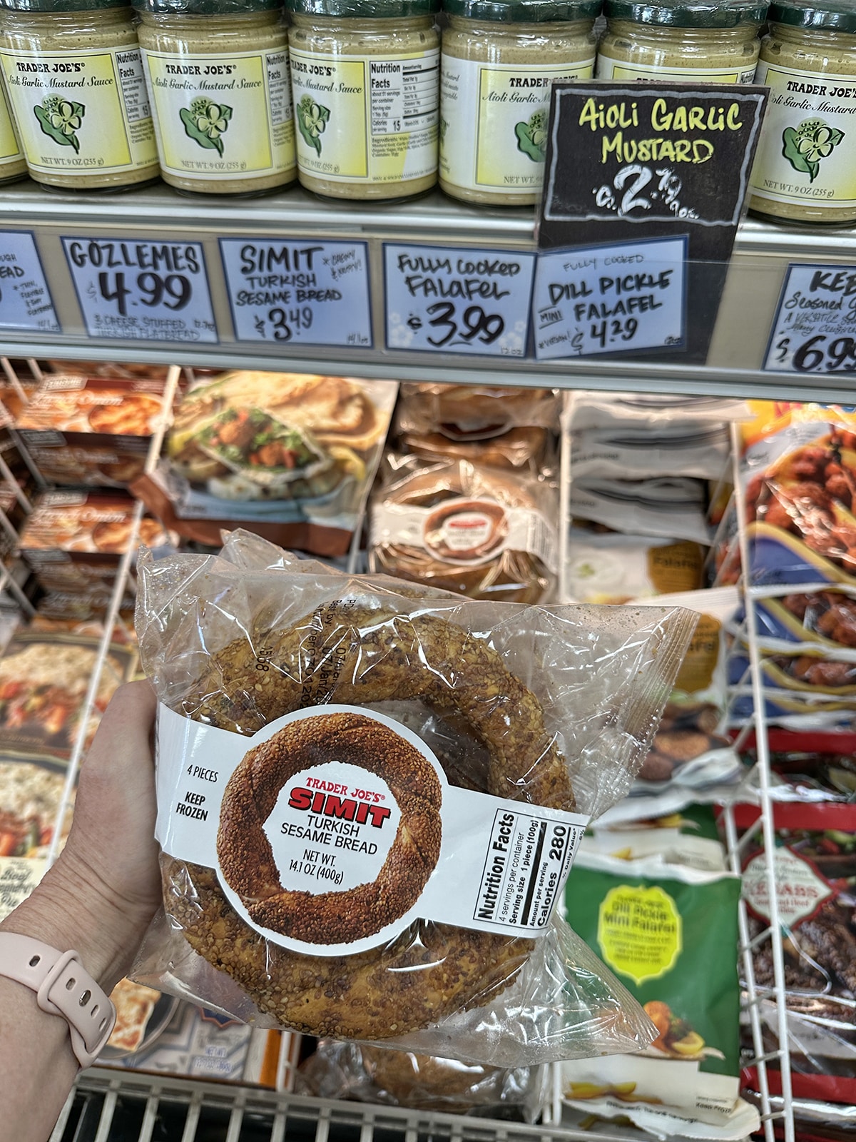 Simit, Turkish sesame bread, being held in front of frozen case at Trader Joe's.