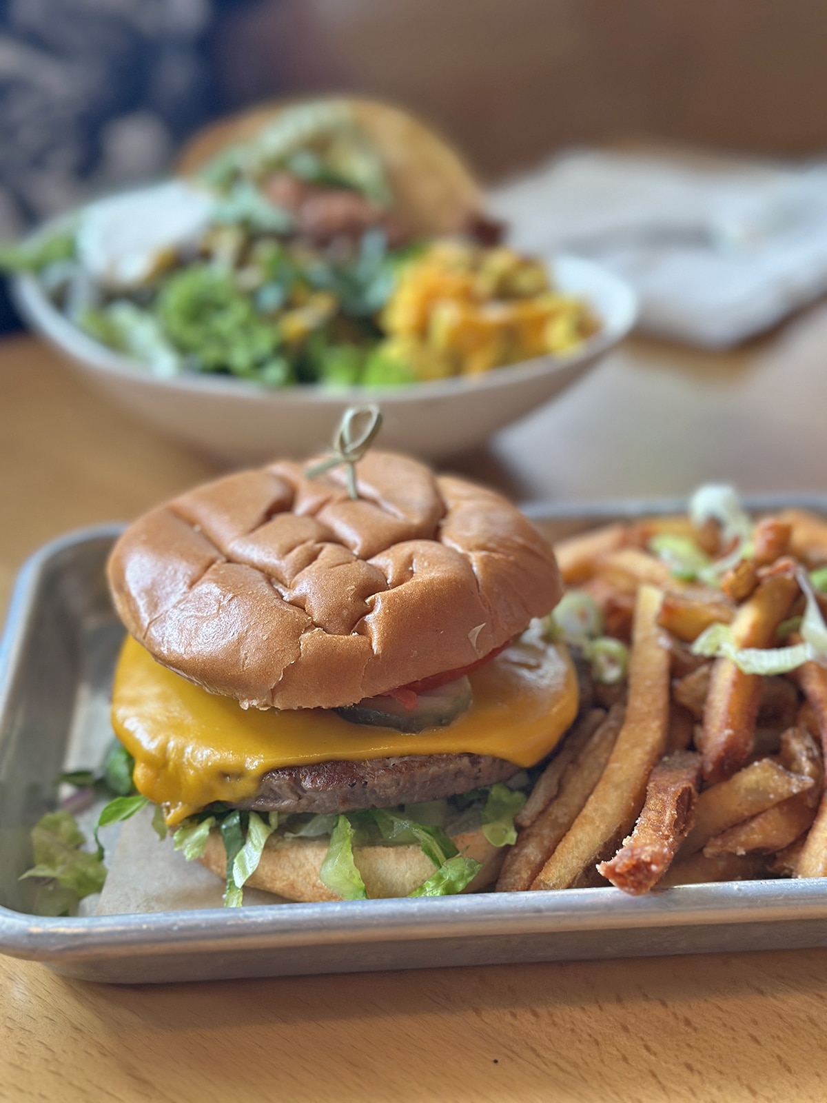 Vegan burger with non-dairy cheese in metal tin with crispy fries.
