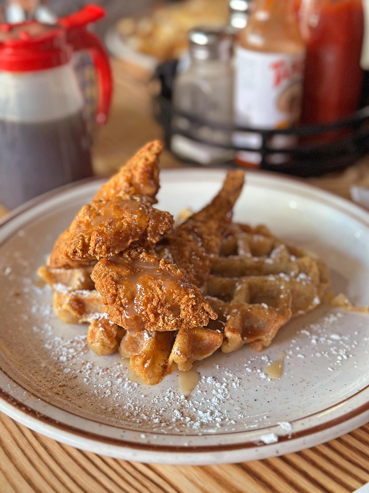 Breaded vegan chicken on waffle dusted with powdered sugar.