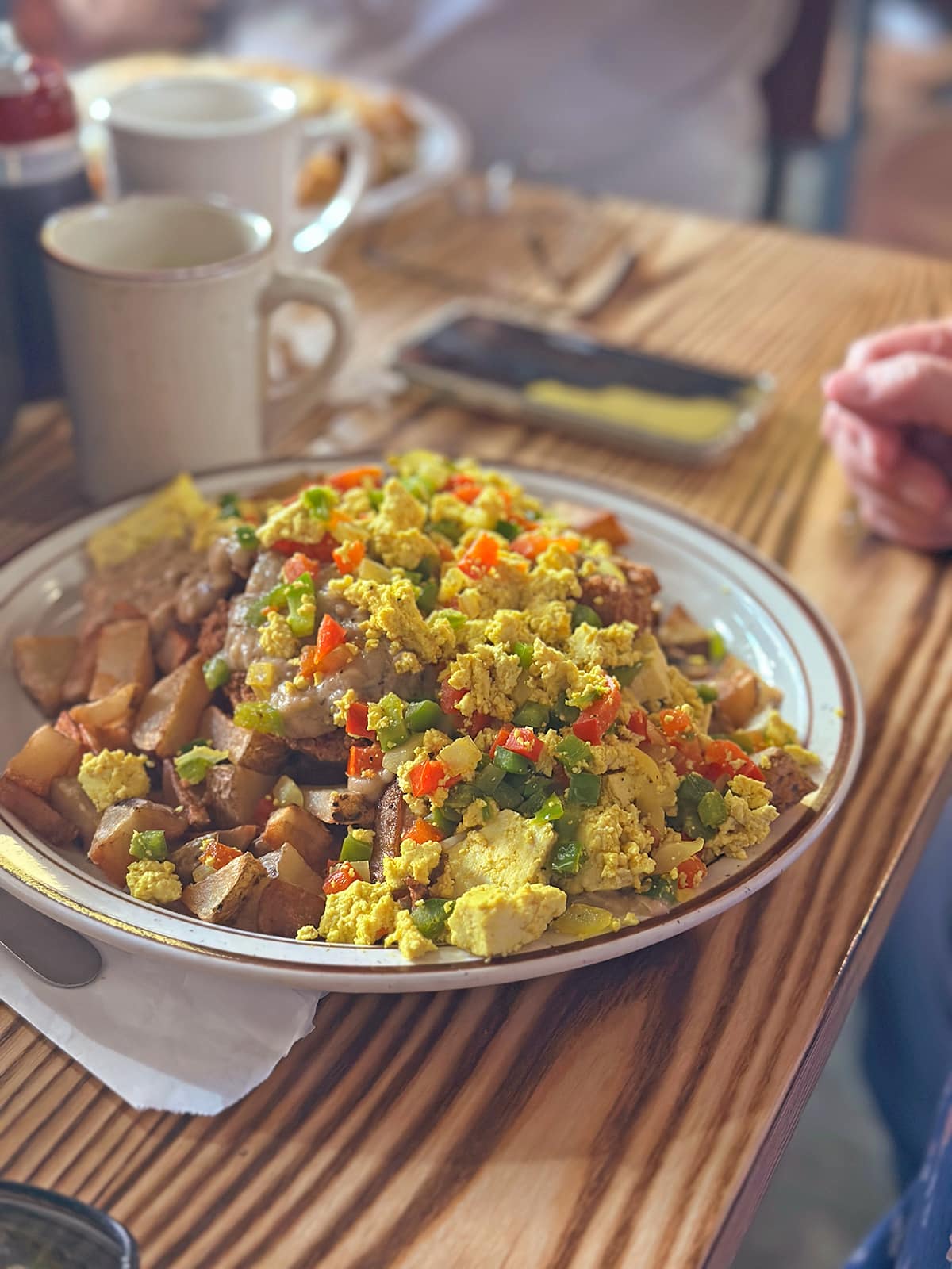 Tofu scramble, potatoes, and gravy on plate by coffee at Railroad Bill's Dining Car.