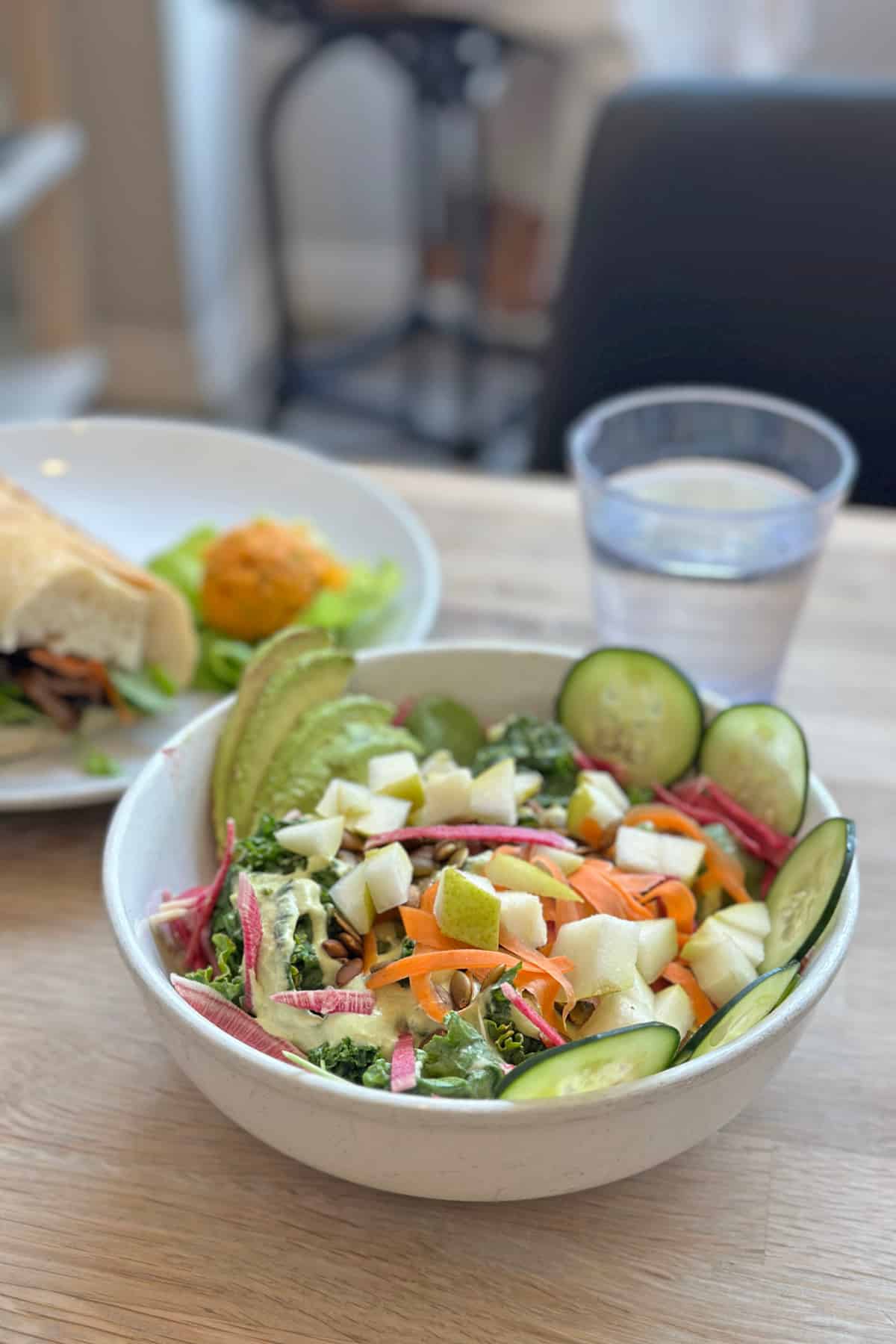Wellness salad with kale, cucumbers, avocado, and carrots in a creamy lemon dill dressing.