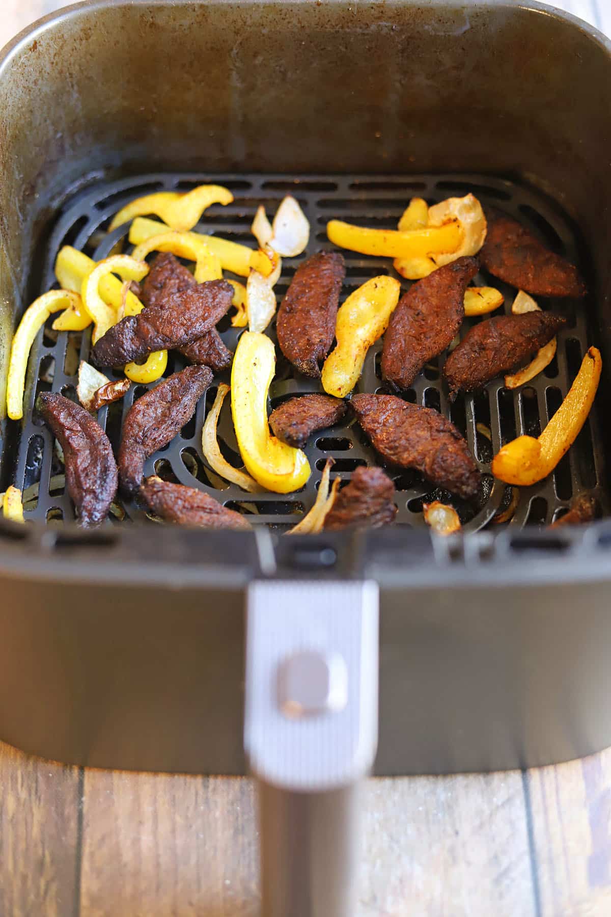 Beefless bulgogi in air fryer basket with peppers and onions.