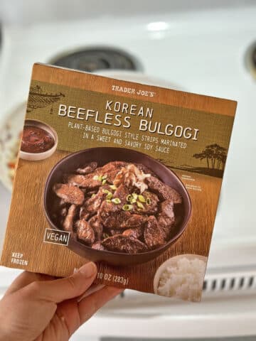 Hand holding package of Trader Joe's beefless bulgogi in front of stove.