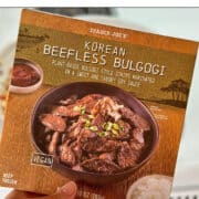 Text overlay: 5 ways to use Trader Joe's beefless bulgogi, cadryskitchen.com. Hand holding package of vegan bulgogi.