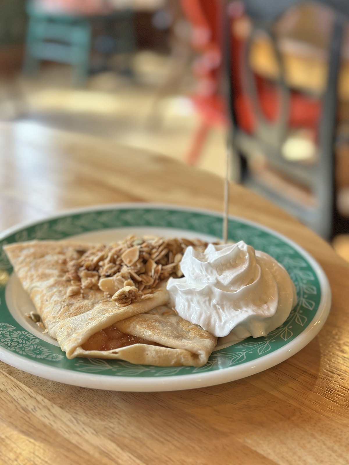 Pillowy pile of vegan whipped cream on plate with apple crumble crepe.
