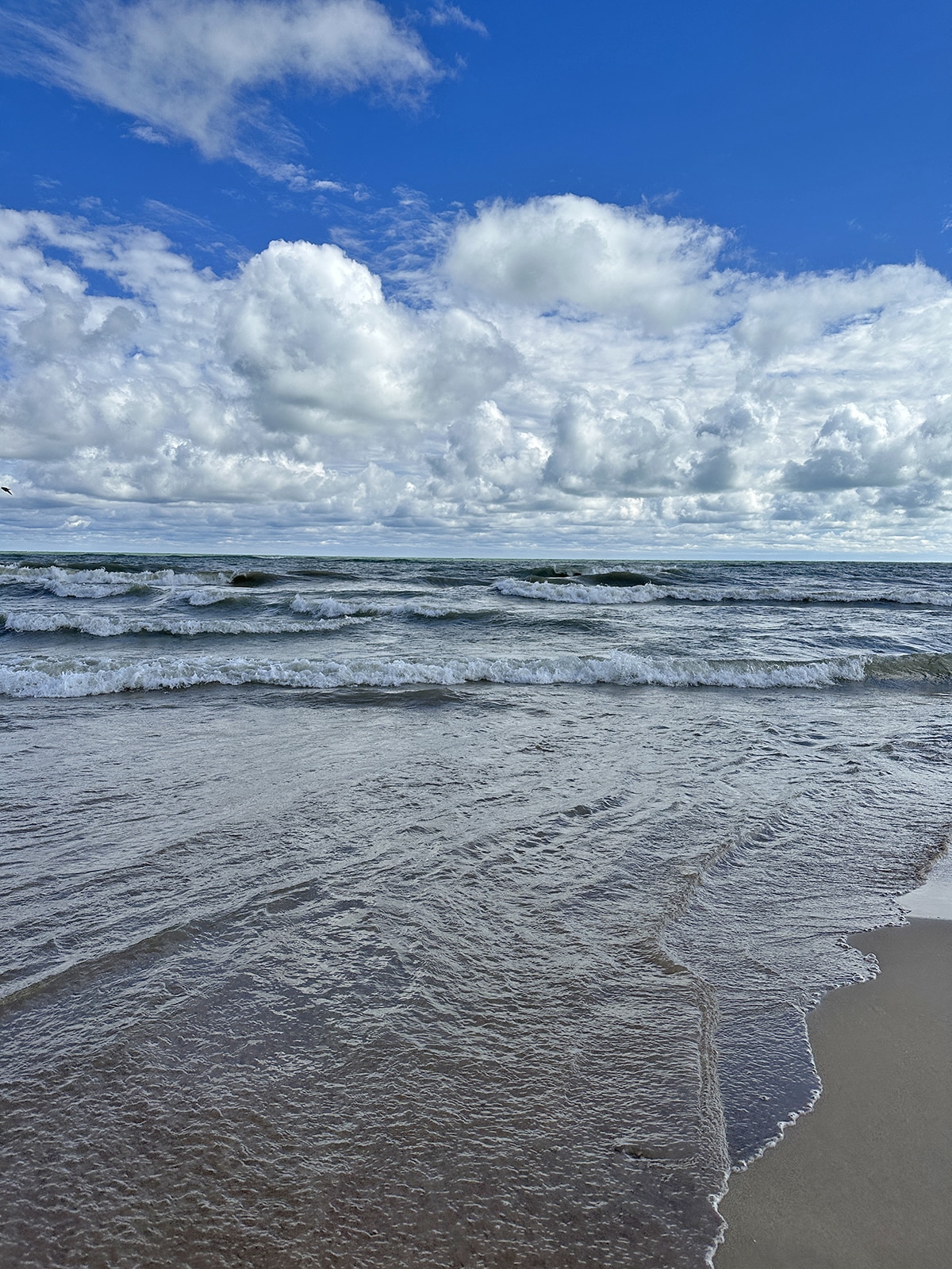 Rolling waves in Lake Michigan with crystal blue sky above at Bradford Beach.