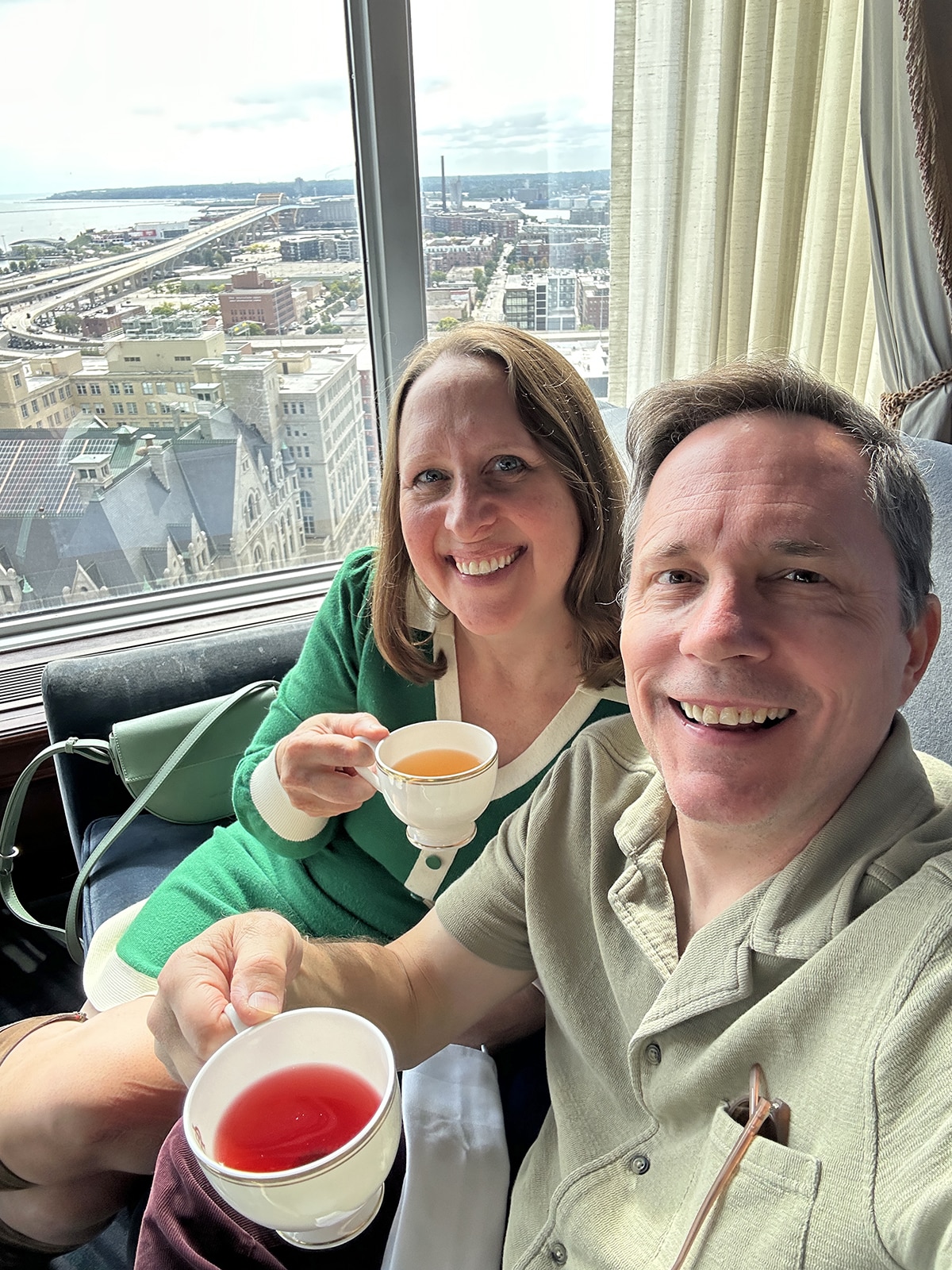 Cadry and David holding mugs of tea in front of window over Lake Michigan.