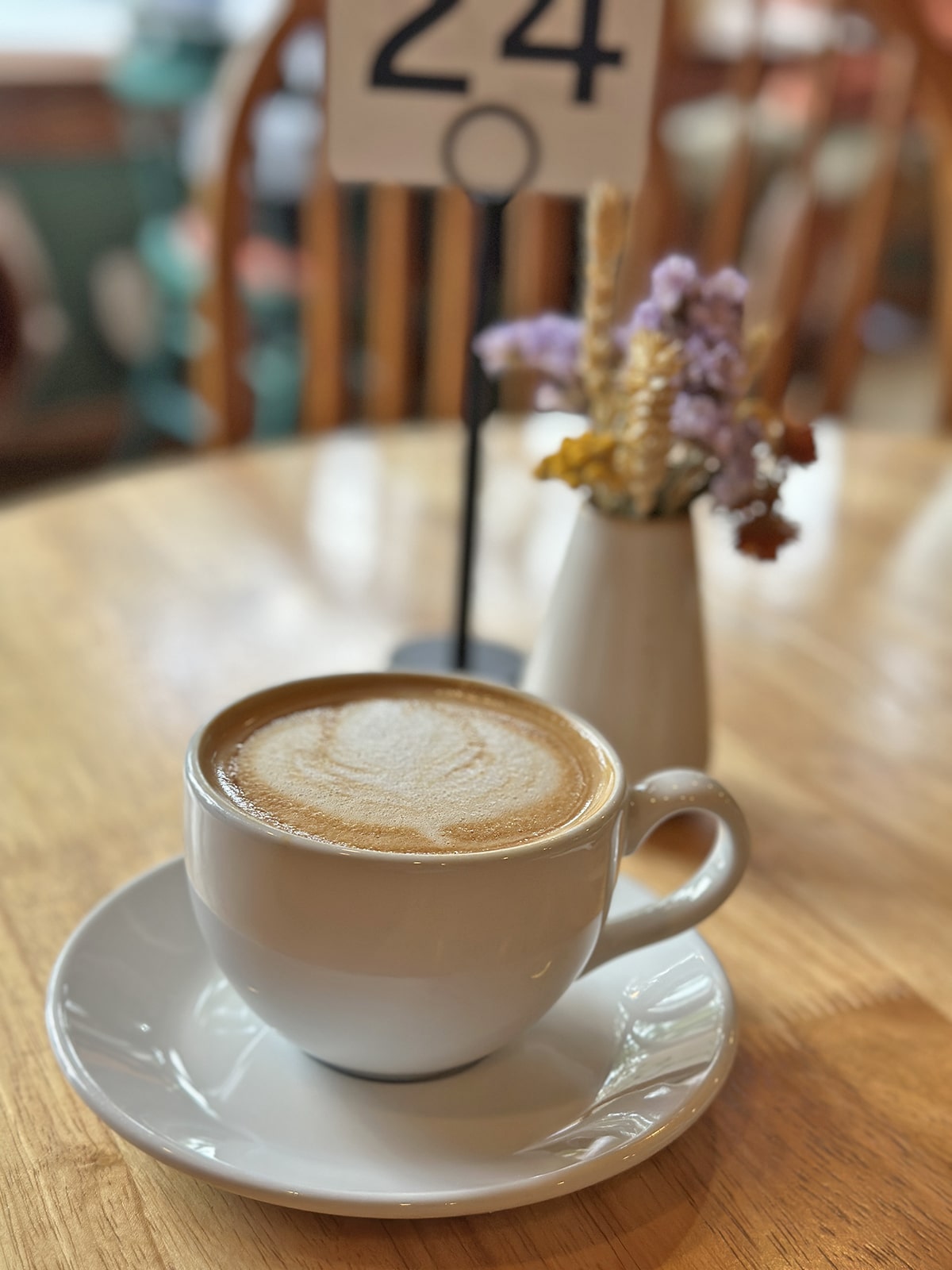 Oat milk latte on table by dried flowers.