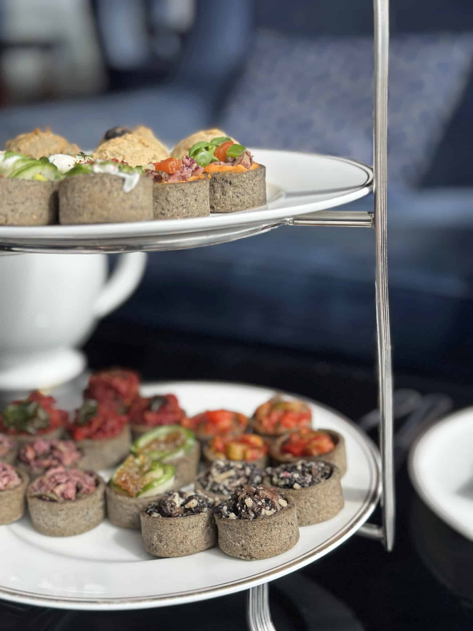 Savory tarts on stacked plates with sun-dried tomato hummus, kalamata olives, mushrooms, and cucumbers.