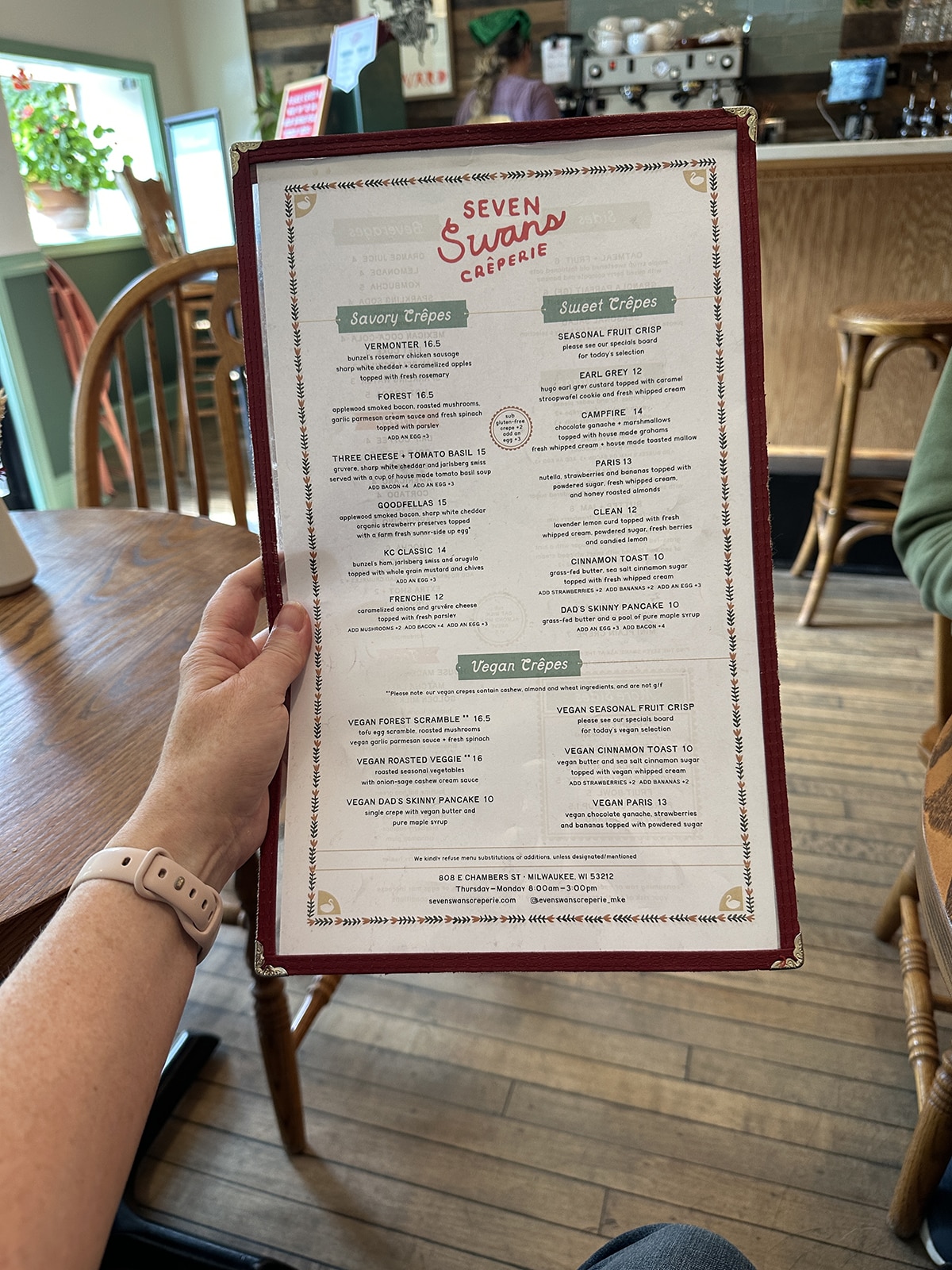 Hand holding Seven Swans Creperie menu.