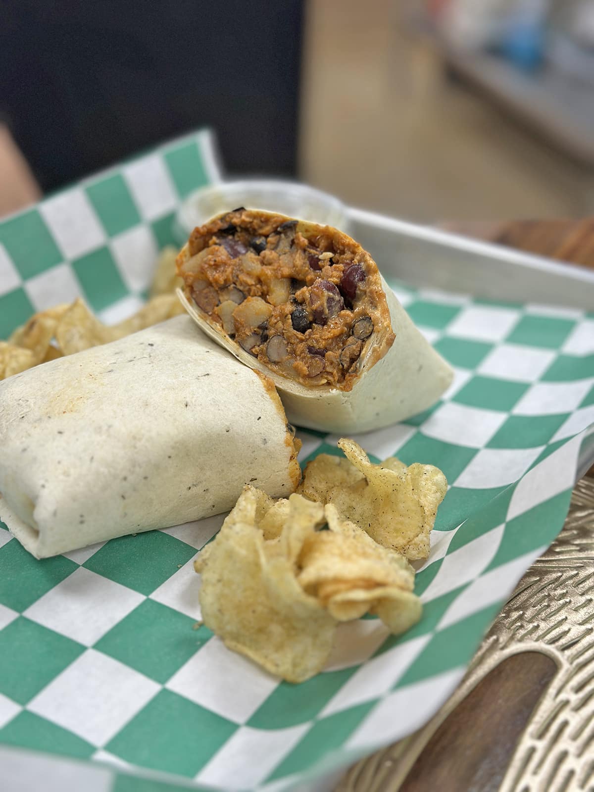 Bean and potato burrito with potato chips on tray.