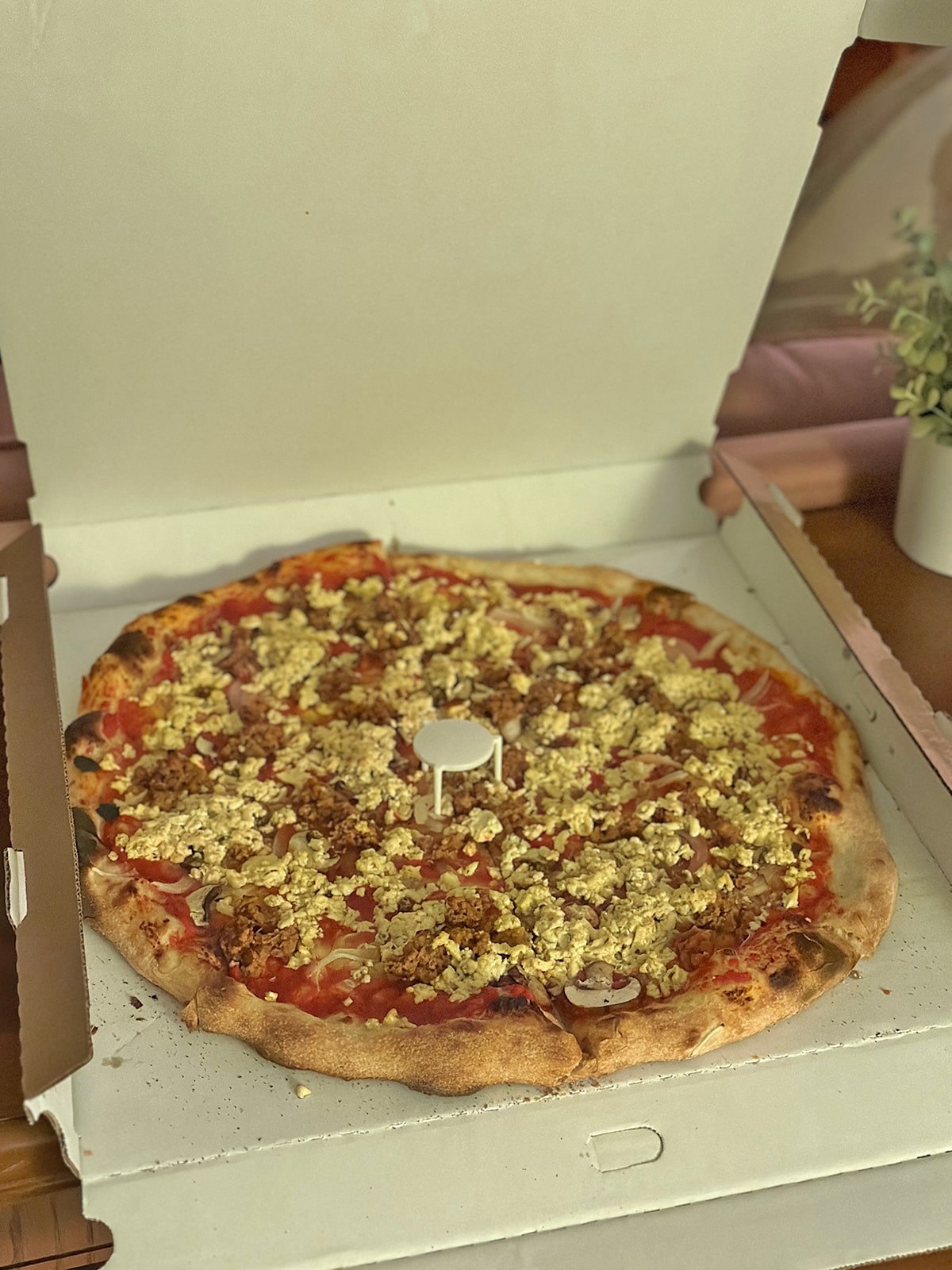Vegan MKE pizza with vegan sausage, mushrooms, and tofu cheese in box.