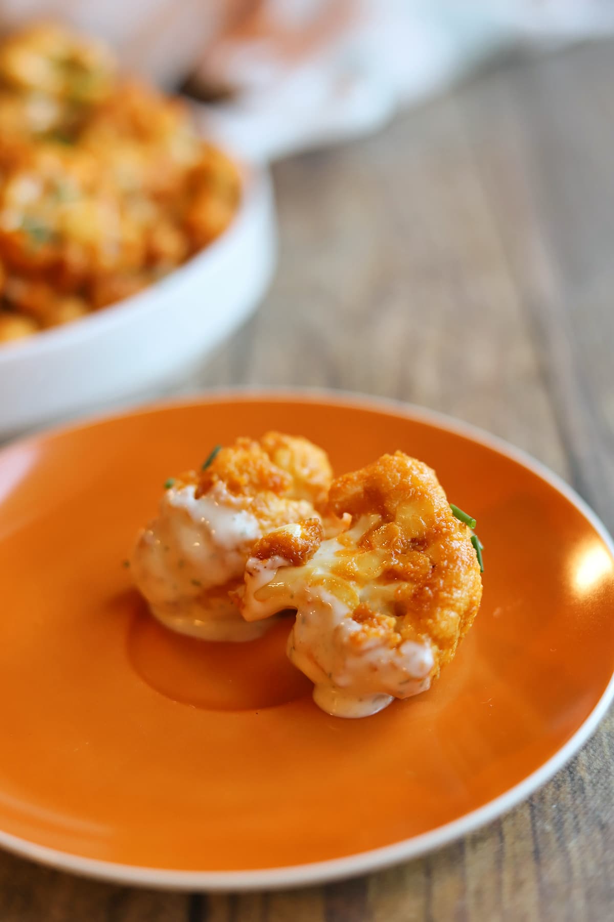 Cauliflower florets coated in buffalo sauce and dressing on plate.