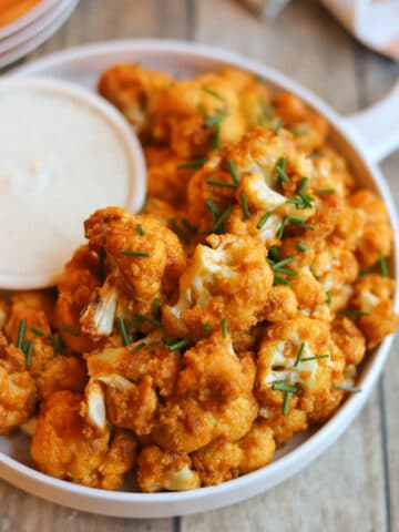 Air fryer buffalo cauliflower on plate with onion and garlic dressing.