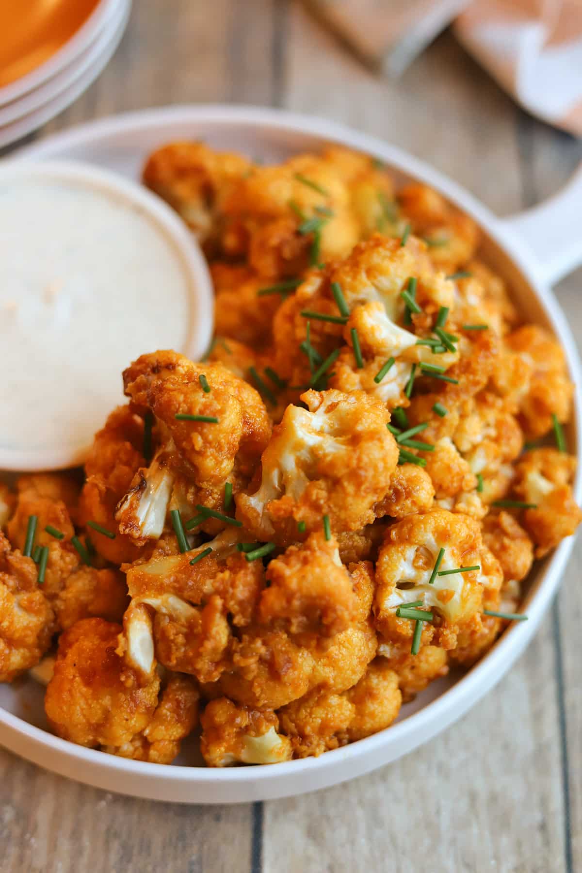 Air fryer buffalo cauliflower on plate with onion and garlic dressing.