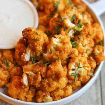 Air fried buffalo cauliflower on platter with vegan dipping sauce.