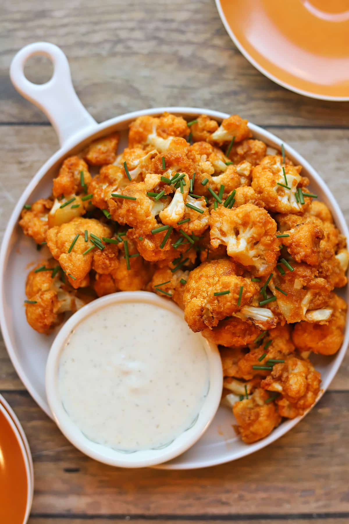Buffalo cauliflower wings on plate with onion and garlic dressing for dipping.